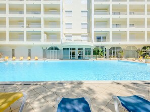 A hotel pool area with multiple levels of balconies, a covered seating area, and a clear view of the pool. - Apartment  by Interhome (Vilamoura)