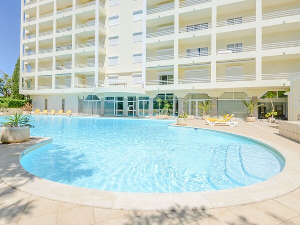 Ein modernes Hotel mit einem zentralen Schwimmbad, mehreren Balkonen und Außenbereichen zum Sitzen.