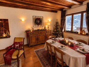 A dining area with a wooden table set for a meal, a Christmas tree, and a fireplace. - House on the edge of the forest in La Claquette (La Broque)