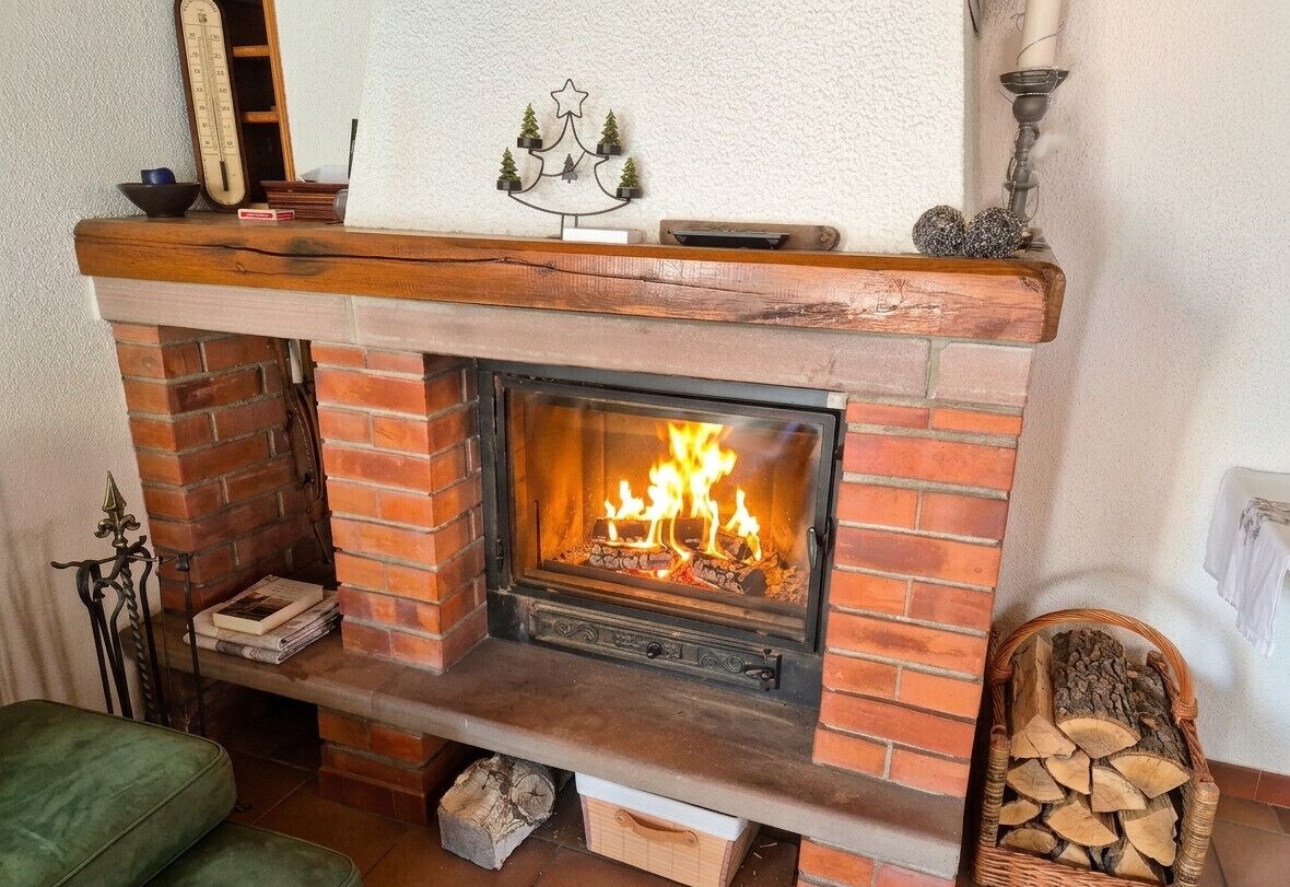 A brick fireplace with a fire, a mantel shelf with decorative items, and a green upholstered bench.