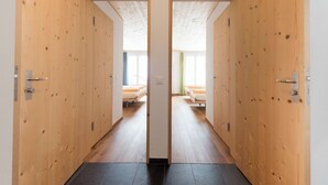 Ein Flur mit Holztüren, die zu einem Zimmer mit Bett und Fenster führen.