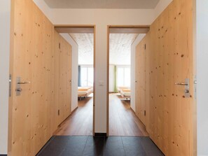 A hallway with wooden doors leading to a room with a bed and a window. - Ferienhaus Isla, (Nufenen), by Interhome (Nufenen)
