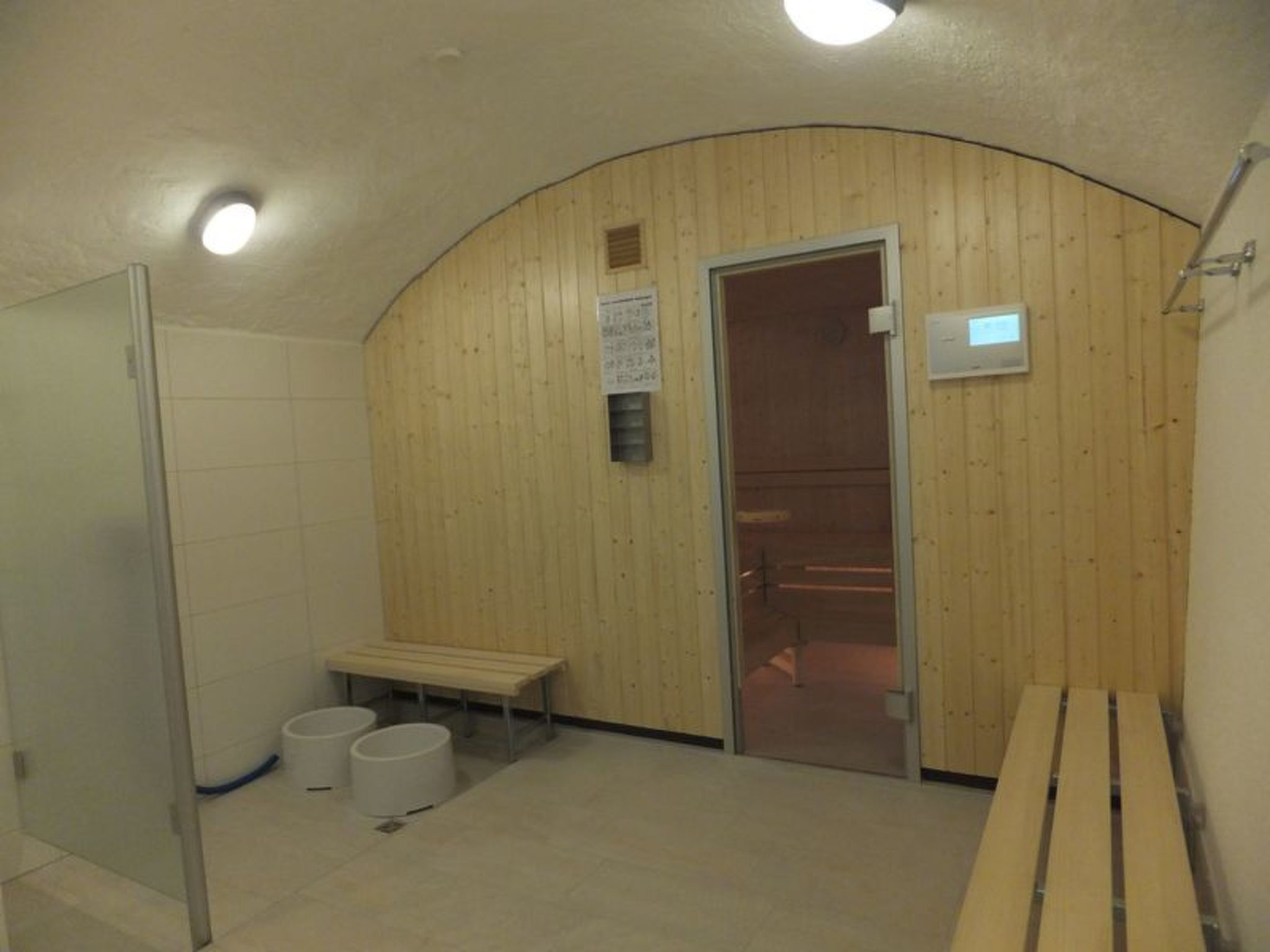 A sauna room with wooden walls, a bench, and two buckets.
