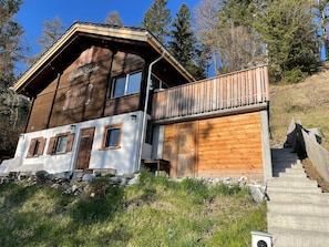 A wooden chalet with a balcony, stone foundation, and a staircase leading up. - Traunter Lareschs, (Feldis), by Interhome (Tomils)