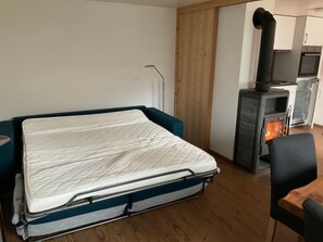 Huone, jossa on sänky, pieni keittokomero ja puuliesi.