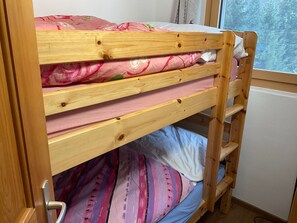 Uma cama beliche com estrutura de madeira e roupa de cama rosa.