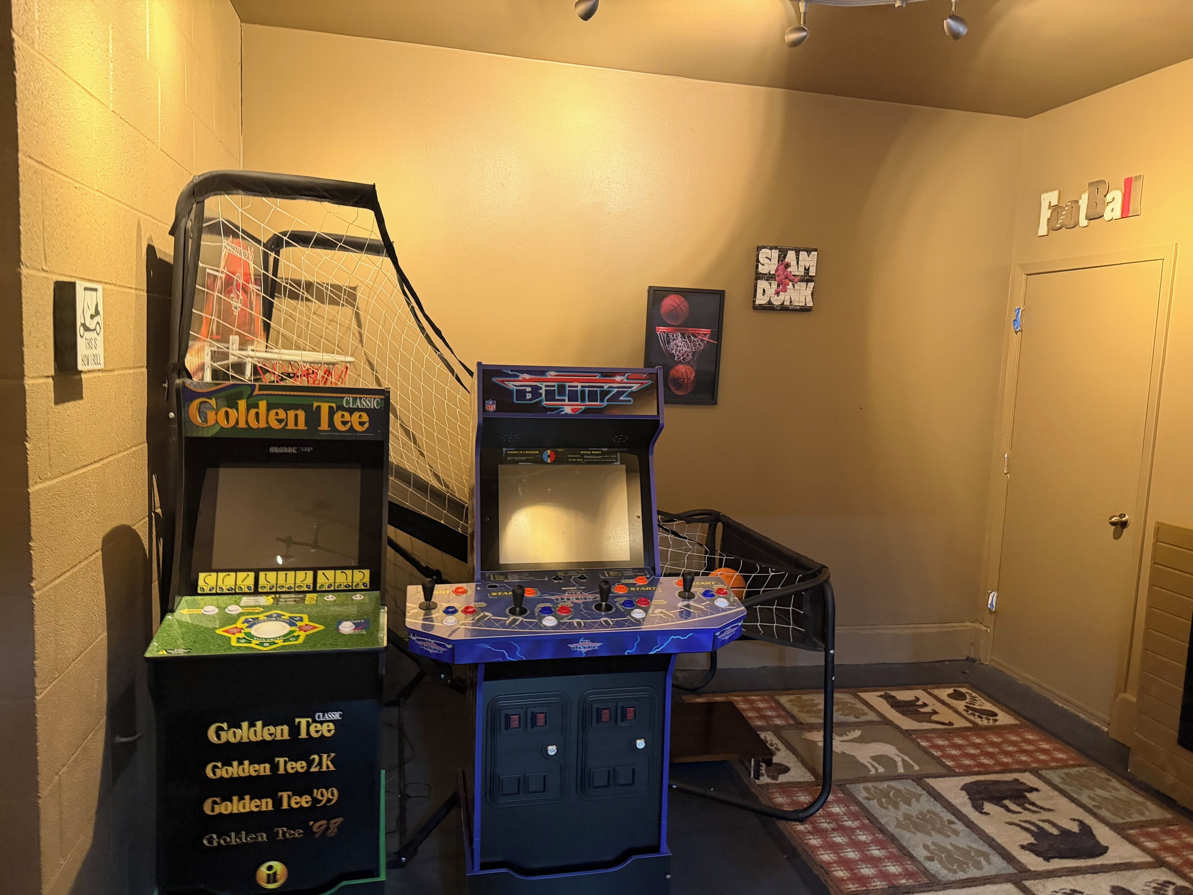 En korridor med arkadspel, inklusive ett Golden Tee-spel och ett Blitz-spel, och en dörr med skylten ”Tai Ball”.
