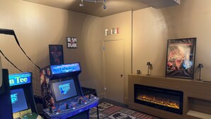Habitación con juegos de arcade, chimenea y una puerta con la leyenda 'Fetal'.