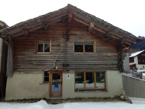 Eine zweistöckige Blockhütte mit Holzfassade, einer Haustür und zwei Fenstern im Erdgeschoss.