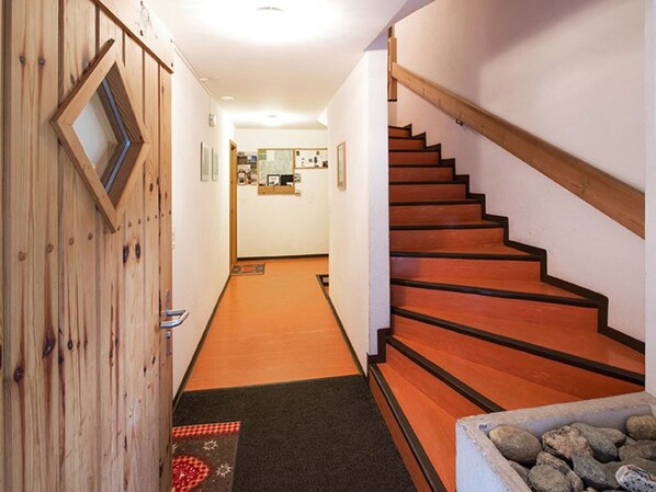 A wooden staircase with a carpeted landing area leading to a room with a desk and a mirror.