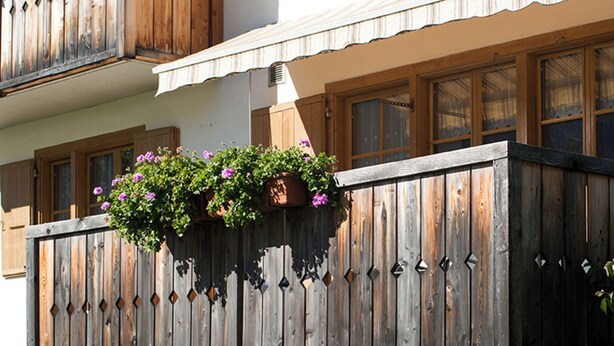 A balcony with wooden railings and hanging flower baskets.