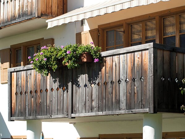 A balcony with wooden railings and hanging flower baskets. - Ferienhaus Muntschi, (Andeer), by Interhome (Andeer)