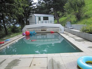 Une piscine avec des jeux gonflables, un petit bâtiment et une zone herbeuse.