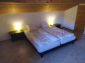 Ein Schlafzimmer mit einem Bett, zwei Nachttischen und einer Holzbalkendecke.