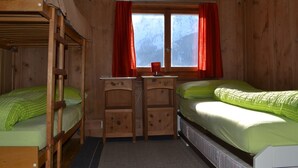 Ein Zimmer in einer Holzhütte mit Etagenbetten, einem Schreibtisch und einem Fenster mit Vorhängen.