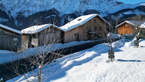 Ein hölzernes Gebäude mit geneigtem Dach, umgeben von schneebedeckten Bergen.