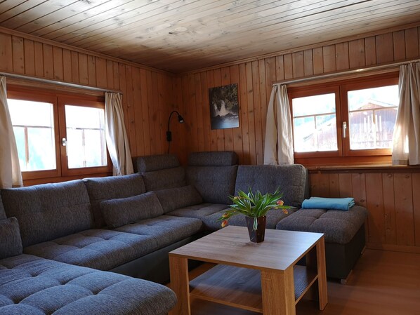 A wooden-paneled room with a sectional sofa, a small table with a plant, and a painting on the wall. - Hof Beeli, (Tschappina), by Interhome (Tschappina)