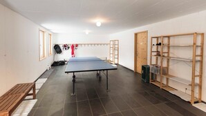 A room with a ping pong table, wooden benches, and shelves. - Ferienhaus Isla, (Nufenen), by Interhome (Nufenen)