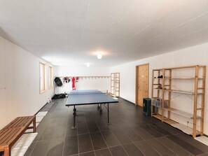 A room with a ping pong table, wooden benches, and shelves. - Ferienhaus Isla, (Nufenen), by Interhome (Nufenen)