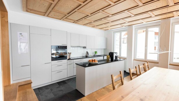 A modern kitchen with white cabinets, a black countertop, and a wooden ceiling. - Ferienhaus Isla, (Nufenen), by Interhome (Nufenen)