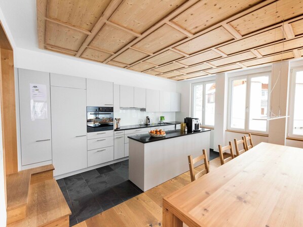 A modern kitchen with white cabinets, a black countertop, and a wooden ceiling. - Ferienhaus Isla, (Nufenen), by Interhome (Nufenen)