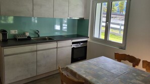 Una cocina con ventana, un lavamanos, armarios y una mesa con sillas.