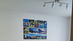Un dormitorio con una cama de madera, una mesita de noche con una lámpara y un cuadro de paisajes colgado en la pared.