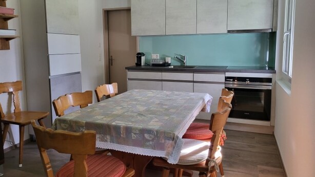 Una cocina compacta con una mesa de comedor, sillas y un refrigerador.