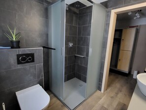 A modern bathroom with a glass-enclosed shower, a toilet, and a sink. - Engadinella, (Splügen), by Interhome (Splügen)