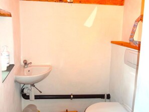 Ein kleines, kompaktes Badezimmer mit einem weißen Waschbecken, einer Toilette und einer Holzausstattung.