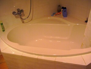 Eine Badewanne mit Duschkopf, eine Shampooflasche und eine Seife.