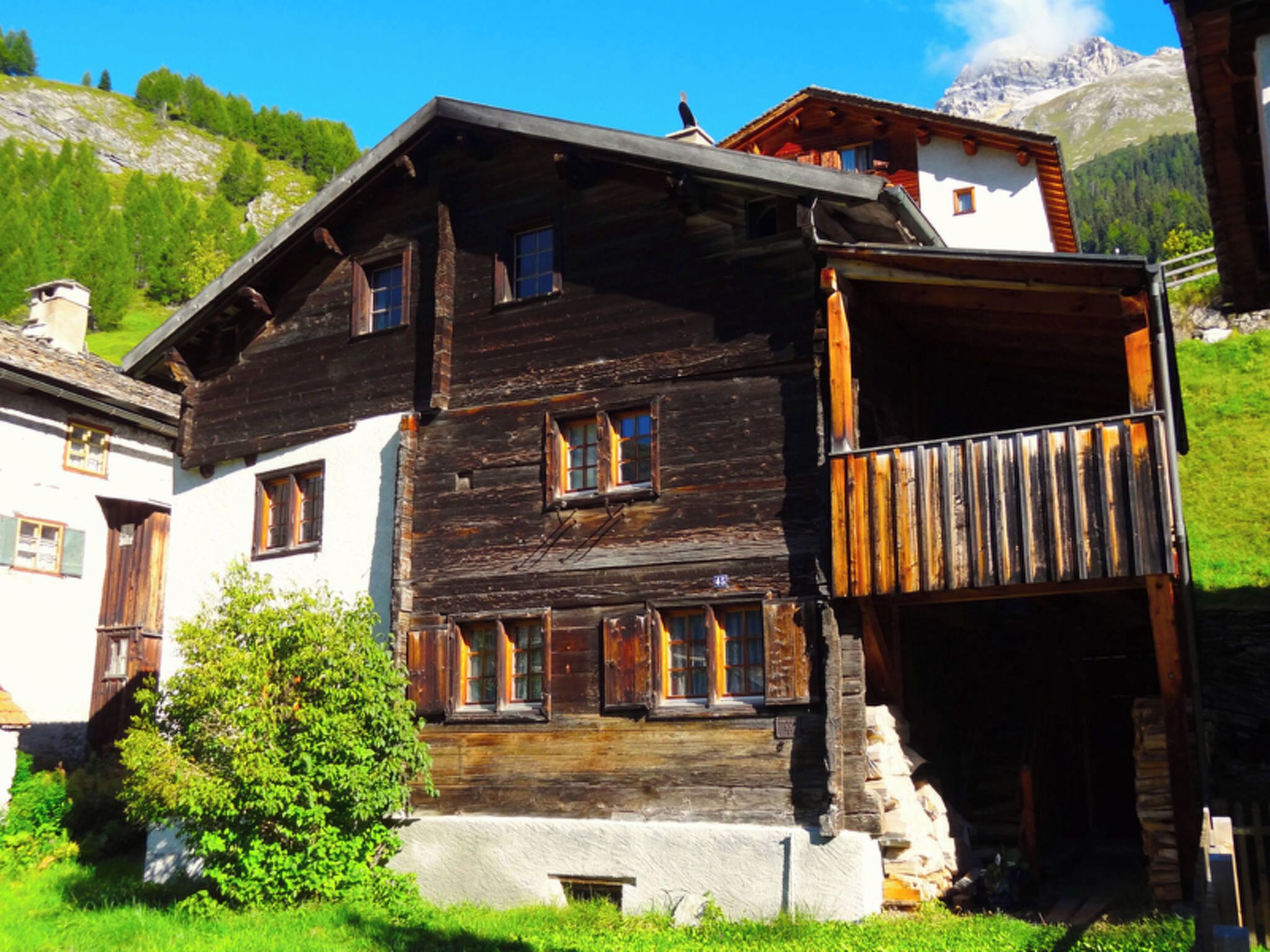 Eine traditionelle Holzhütte mit vielen Fenstern, einem Balkon und einem Steinfundament.