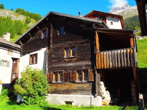 A traditional wooden chalet with multiple windows, a balcony, and a stone foundation. - Haus Nicca, (Splügen), by Interhome (Splügen)