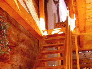 Ein Holzinnenraum mit einer Holztreppe und einer Pflanze mit roten Beeren.