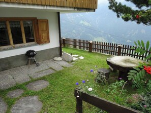 A house with a stone patio, a barbecue grill, and a wooden fence. - Tgea Beala Vesta, (Lohn), by Interhome (Lohn GR)