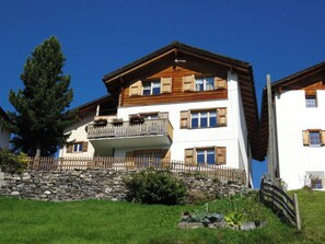 Un edificio a più piani con un balcone, una parete in pietra e un recinto in legno.