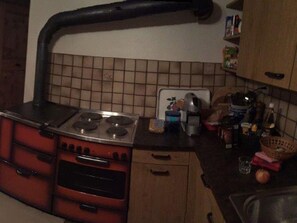 A kitchen with a stove, oven, and a tiled backsplash. - Wohnung Etter Albertinihaus, (Splügen), by Interhome (Splügen)