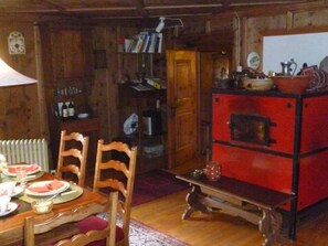 A wooden interior with a dining table set for two, a bookshelf, and a red appliance. - Wohnung Etter Albertinihaus, (Splügen), by Interhome (Splügen)