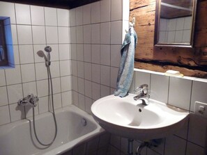 A bathroom with a bathtub, a sink, and a towel hanging on a rack.