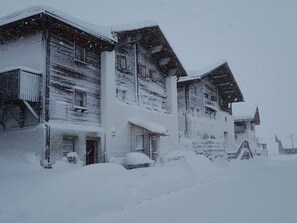 A snow-covered building with multiple levels, a visible staircase, and a front entrance.