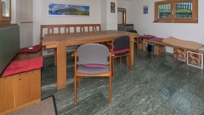 Una habitación con una mesa de madera, sillas, un banco, una chimenea y un cuadro en la pared.