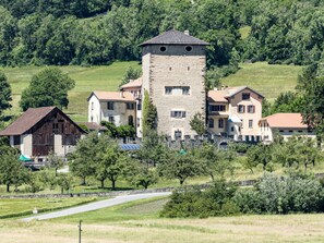 A rural estate with a central tower, multiple residential buildings, and surrounding greenery.