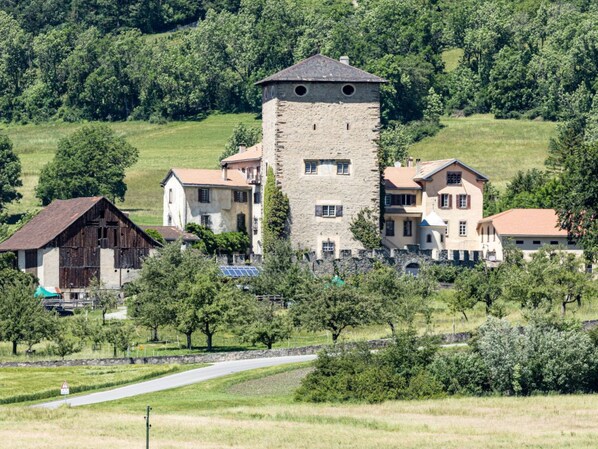 A rural estate with a central tower, multiple residential buildings, and surrounding greenery.