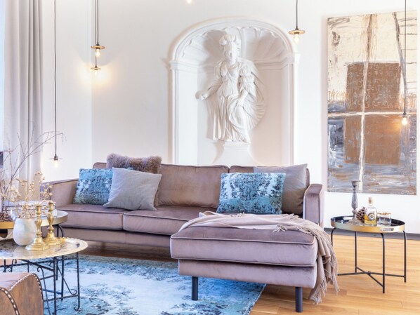 A living room with a sofa, a table, a statue, and a painting.