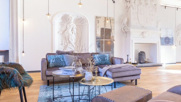 A spacious living room with a sofa, armchairs, a coffee table, and a fireplace.
