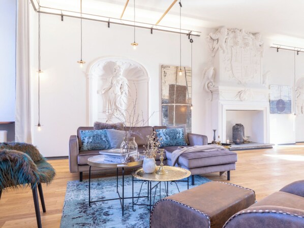 A spacious living room with a sofa, armchairs, a coffee table, and a fireplace.