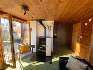A wooden interior with a fireplace, a sofa, a dining area, and a sliding glass door leading to an outdoor space. - Haus Maran, (Oberurmein), by Interhome (Urmein)