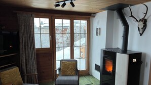 Um quarto aconchegante com lareira, sofá, poltrona e televisão.