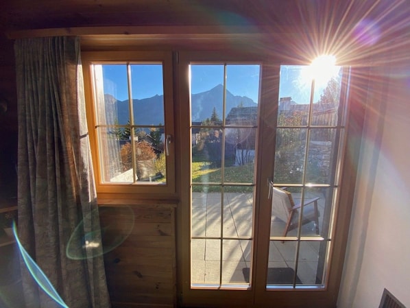 A room with a large window offering a view of mountains and a clear sky.
