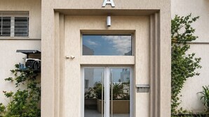 Ein Gebäudeeingang mit einem großen 'A'-Schild, einer Glastür und einem kleinen Fenster darüber.